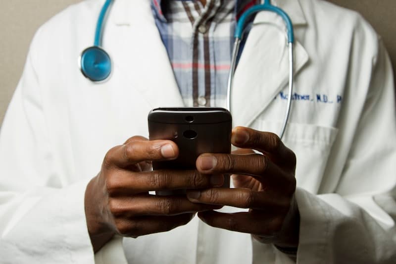 A clinician in a white coat using a handheld device