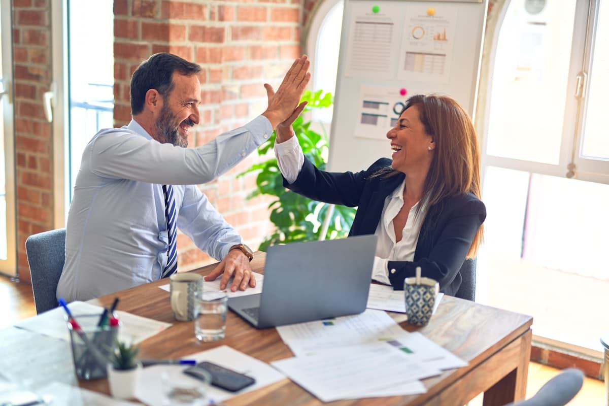 Two colleagues high-fiving across the desk
